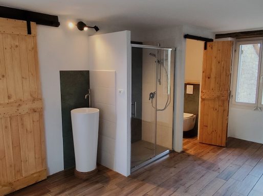 Slaapkamer 2, open badkamer Moderne badkamer met douche, wastafel en houten deuren.